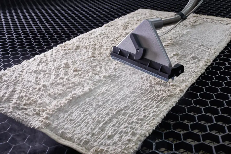 White area rug undergoing professional fine rug cleaning with a vacuum